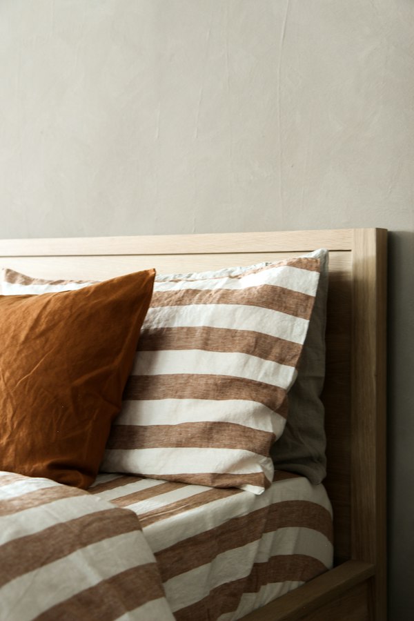 Close-up of a striped linen cushion against a timber headboard